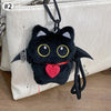 Colgante de gato negro de peluche como llavero, exhibido contra un bolso claro.