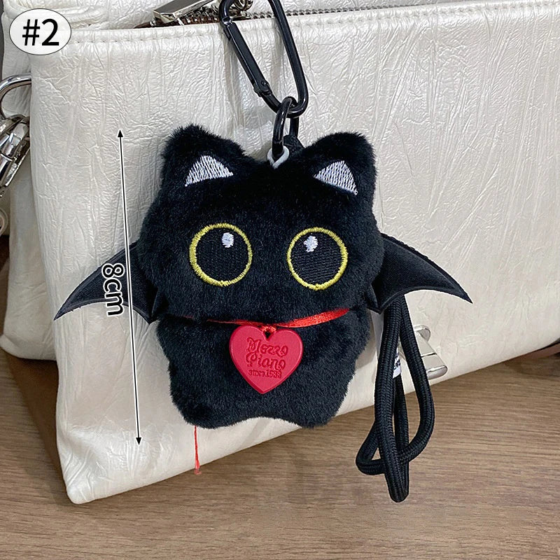 Colgante de gato negro de peluche como llavero, exhibido contra un bolso claro.