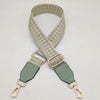 A beige and olive green braided nylon strap for a bag, featuring metal hooks.