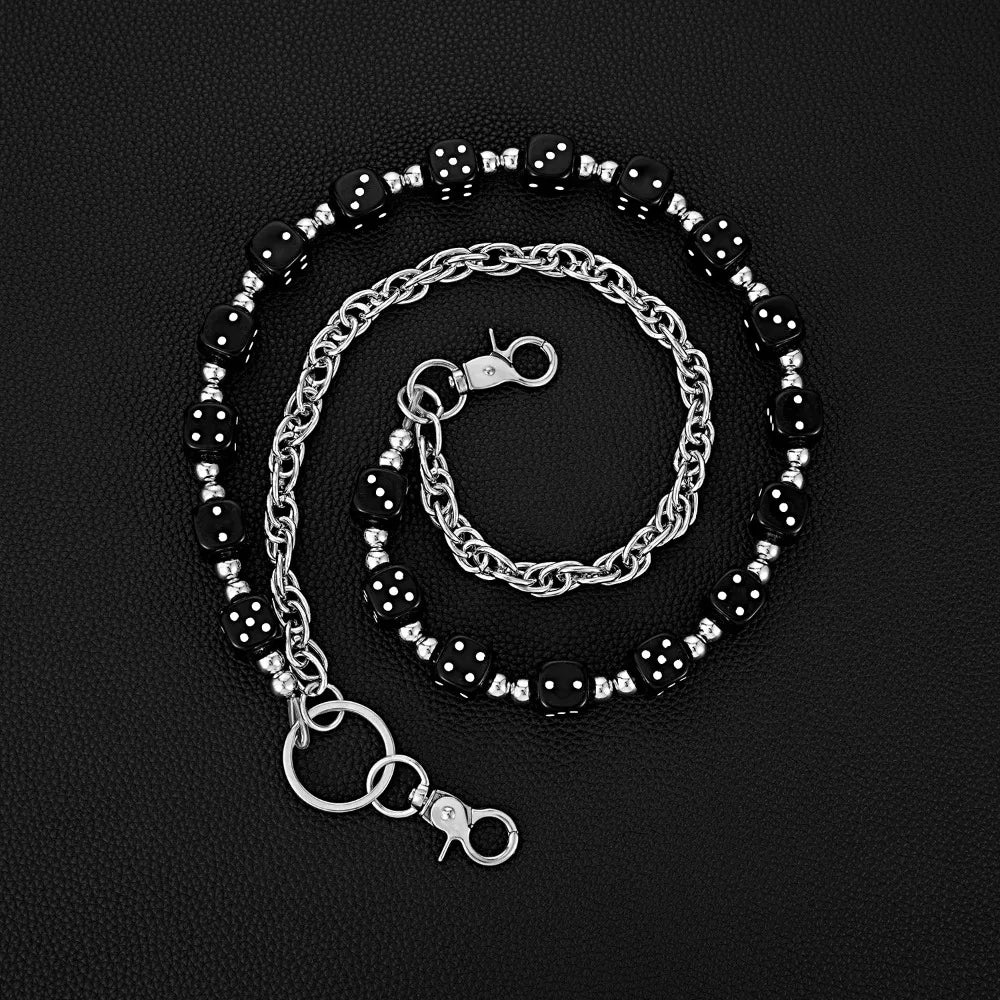 Silver chain bracelet with black beads and a clasp, laid out on a dark surface.