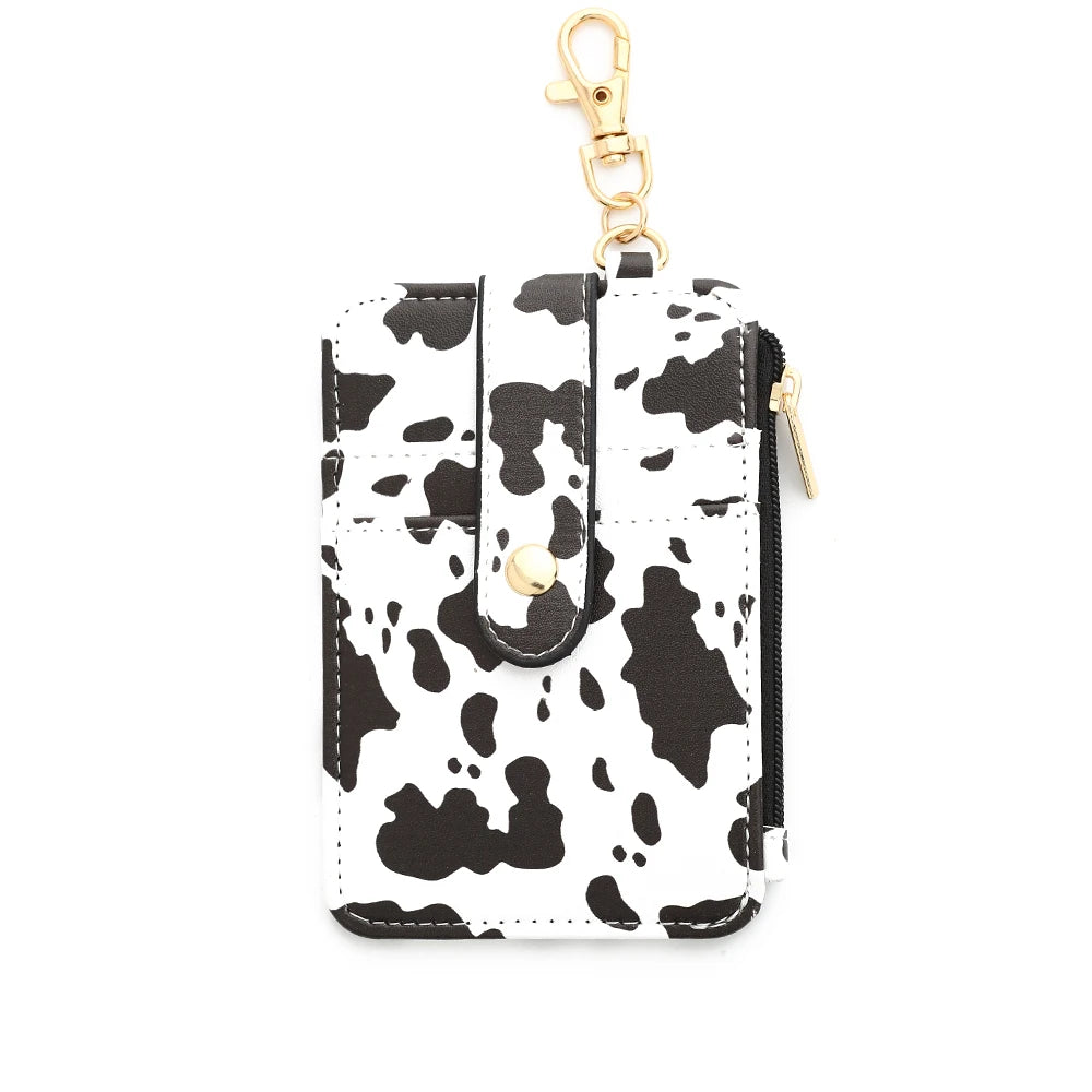 A black and white cow print silicone PU leather key chain wristlet wallet with a gold-colored clasp.