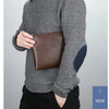 A man wearing a grey sweater is holding a brown PU leather clutch wallet.