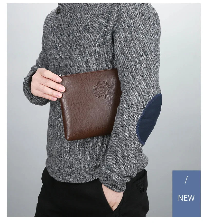 A man wearing a grey sweater is holding a brown PU leather clutch wallet.