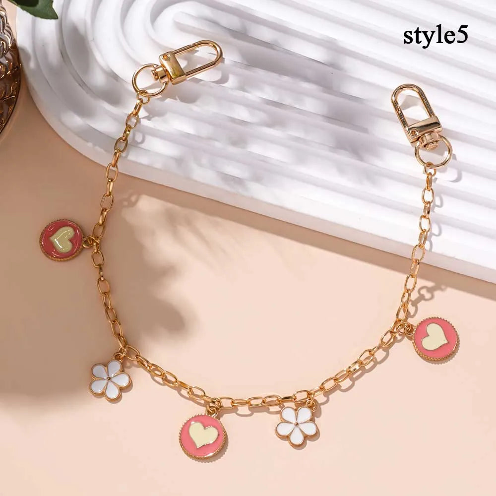 Collar de cadena dorada con corazón de esmalte y adornos de flor de cerezo, mostrado sobre un fondo claro.