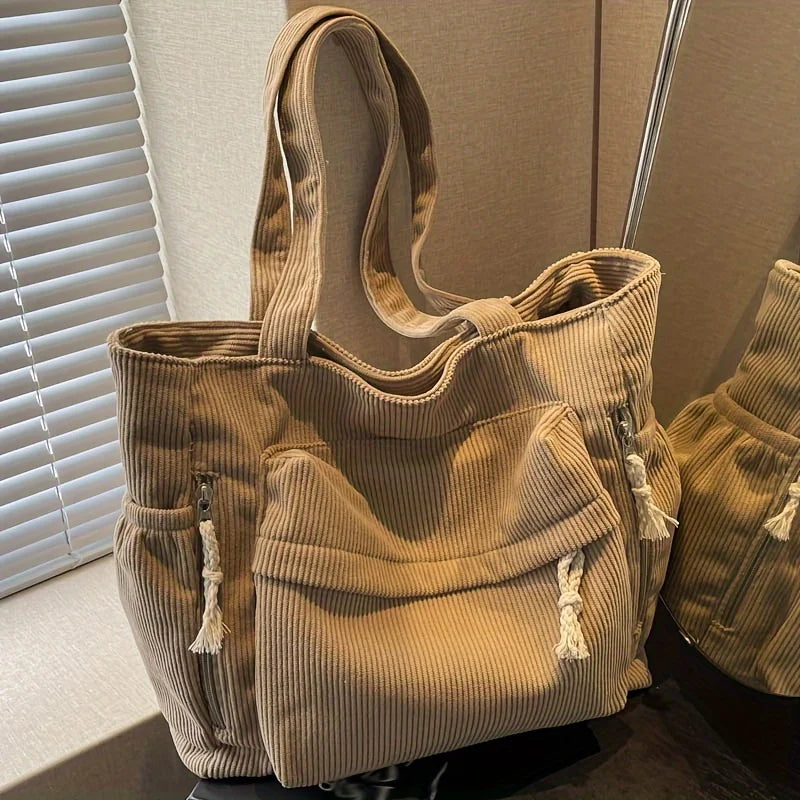 Sac cabas en velours côtelé beige avec plusieurs poches, exposé sur fond clair.