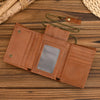 A brown genuine leather trifold wallet with a rectangular window and a detachable gold-colored chain resting on a wooden surf