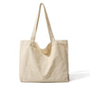 A beige canvas shoulder tote bag hanging against a white background.