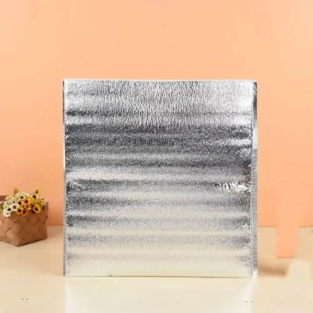 A rectangular silver insulated thermal food delivery bag with a textured aluminum foil lining.