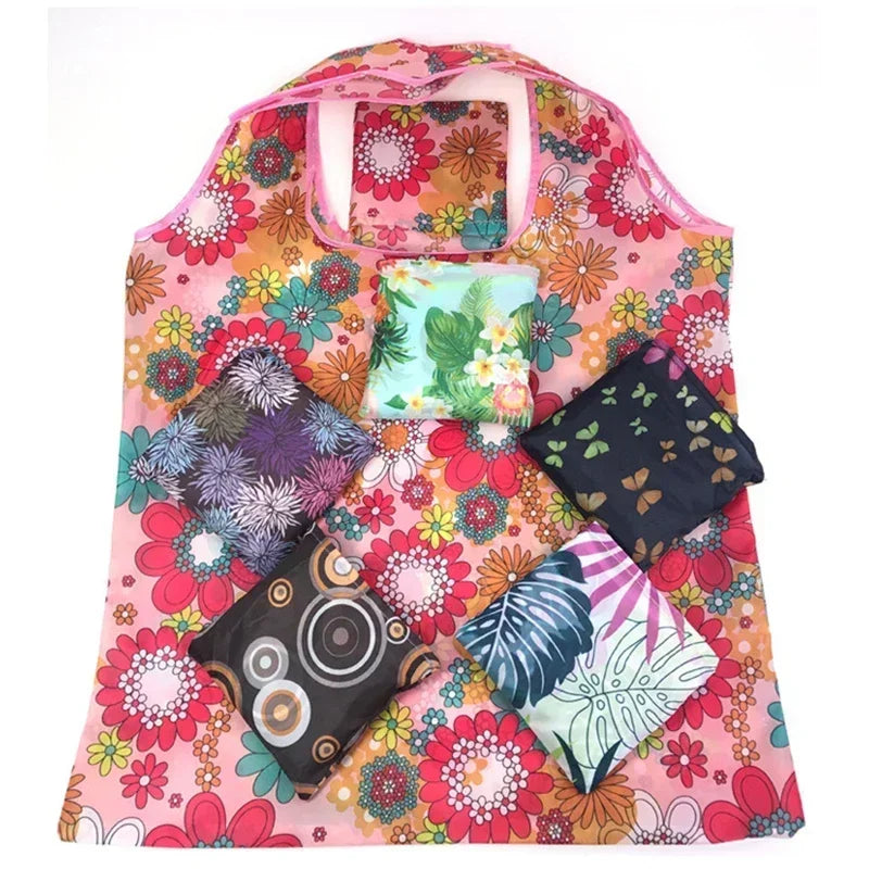 A pink floral print tote bag featuring various colorful flower patterns and a transparent pocket.