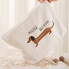 A beige corduroy makeup storage bag featuring a brown dachshund silhouette with text on it.