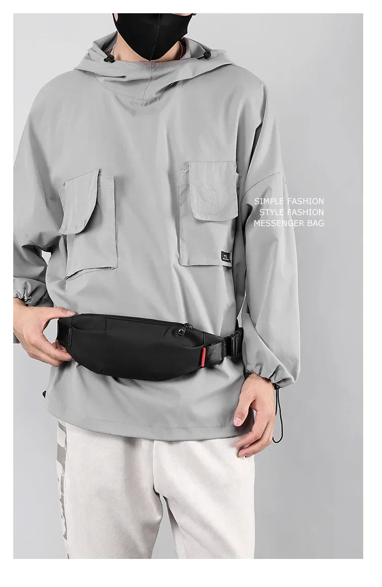A person wearing a gray hooded jacket is holding a black messenger bag.