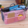 A pink multi-pocket organizer tote bag filled with cosmetics, tools, and small essentials.