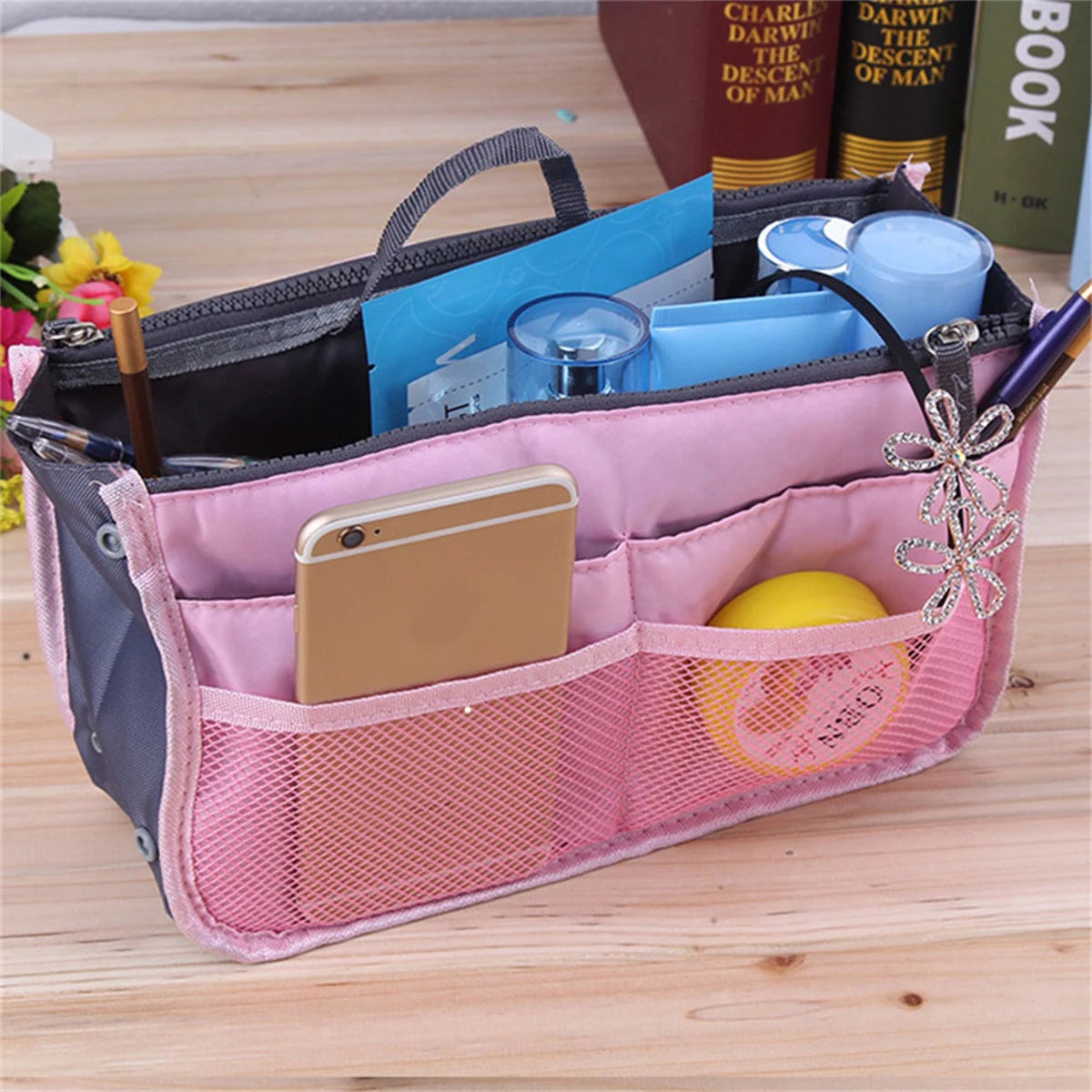 A pink multi-pocket organizer tote bag filled with cosmetics, tools, and small essentials.