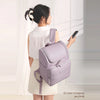 A woman is holding a light purple insulated travel backpack and a smartphone in a bright indoor setting.