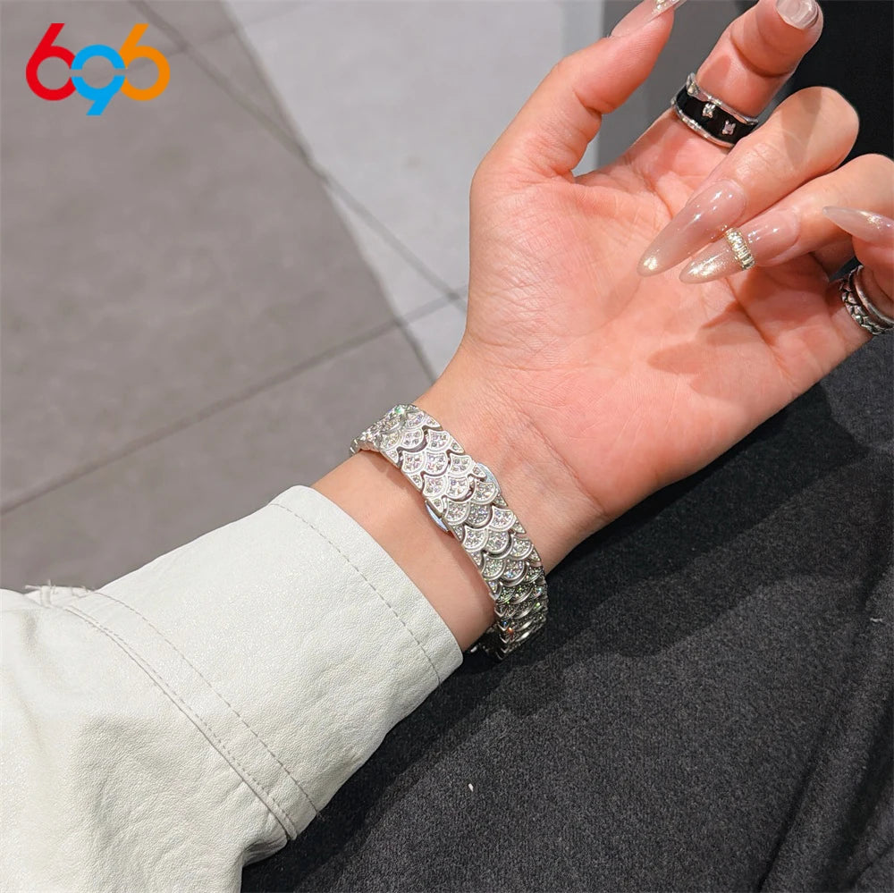 A hand is wearing a sparkling metal watch band with fishscale texture on a wrist.