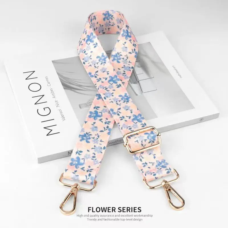 A floral patterned nylon bag strap in light blue and pink is displayed on a white box.