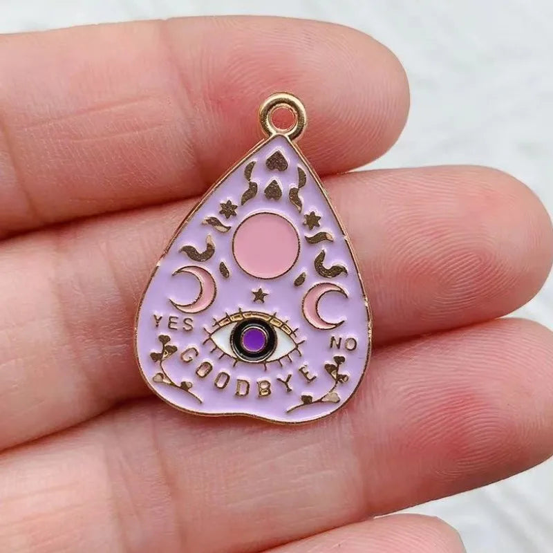 A pink teardrop-shaped celestial charm featuring a crescent moon, star, and an eye design.