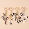 Gold enamel heart keychains featuring various shapes including a shoe, bow, and number 5.