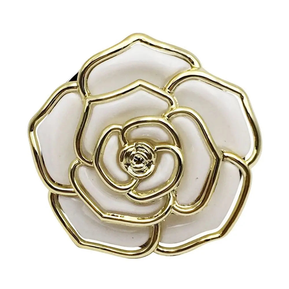 A gold-toned metal flower shaped bag hook with layered petals and a white center.