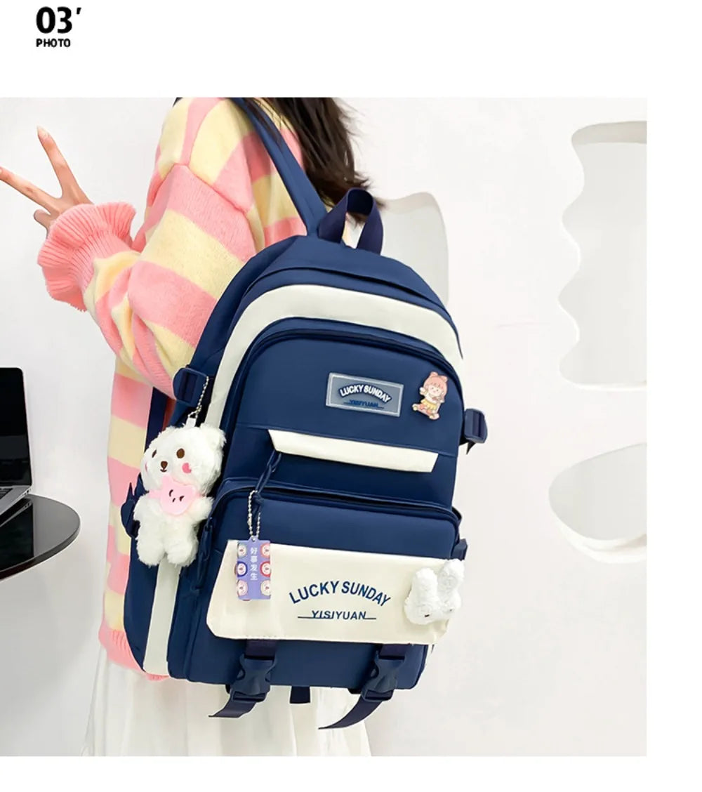 A navy blue nylon backpack set featuring a cartoon design and white accents, worn by a person.