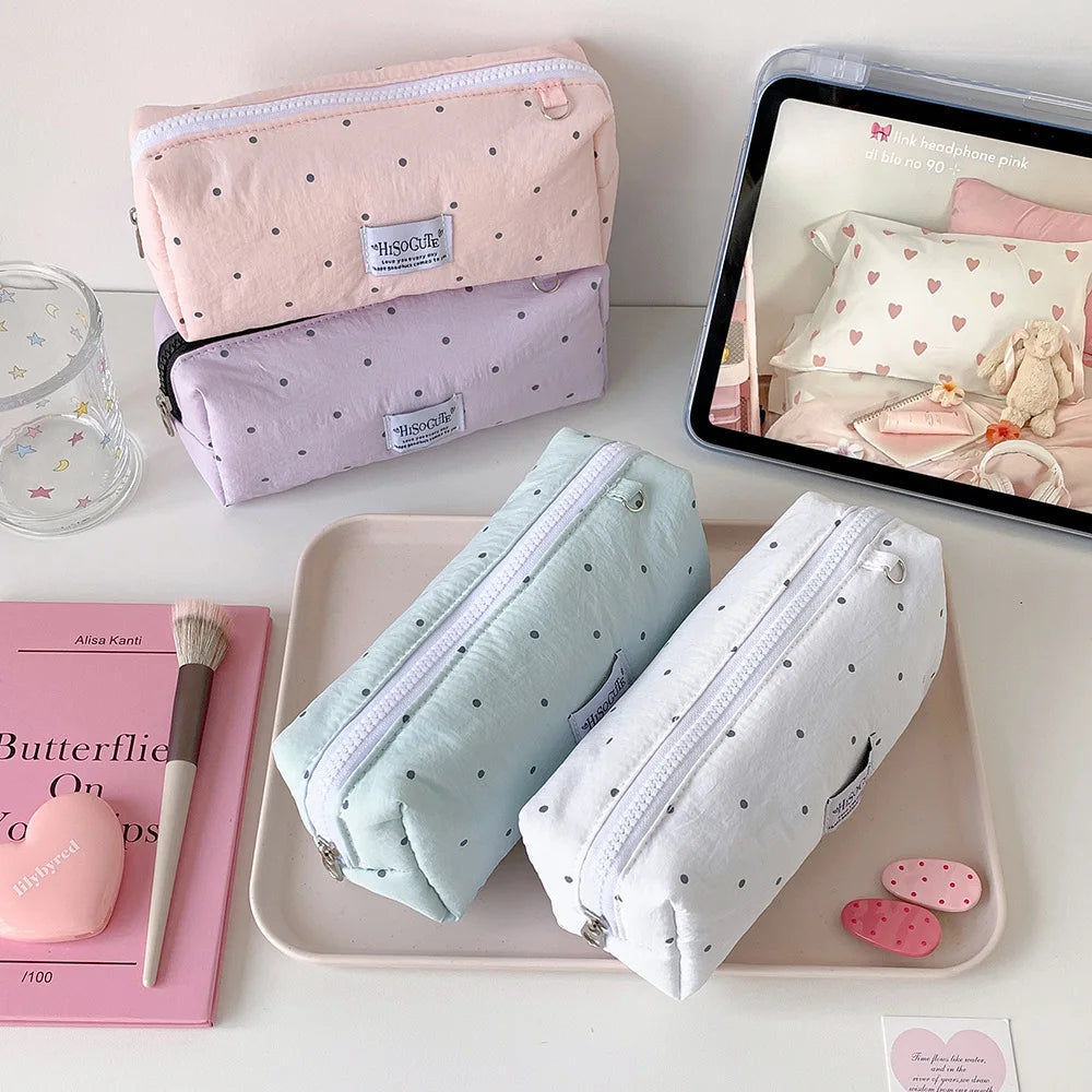 Eine Sammlung von rosa und hellblauen Bleistifthaltern, darunter eine große Polka-Dot-Hülle, präsentiert auf einem rosa Table