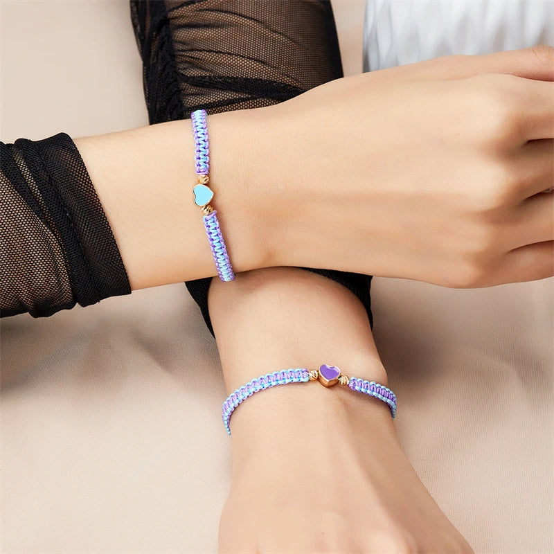 A close-up of two beaded friendship bracelets worn on a wrist, featuring light blue and purple beads.