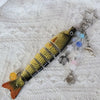 A yellow and black simulation fish keychain with a gold tail and various charms.