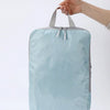 A light blue vertical travel organizer bag being held by a hand.