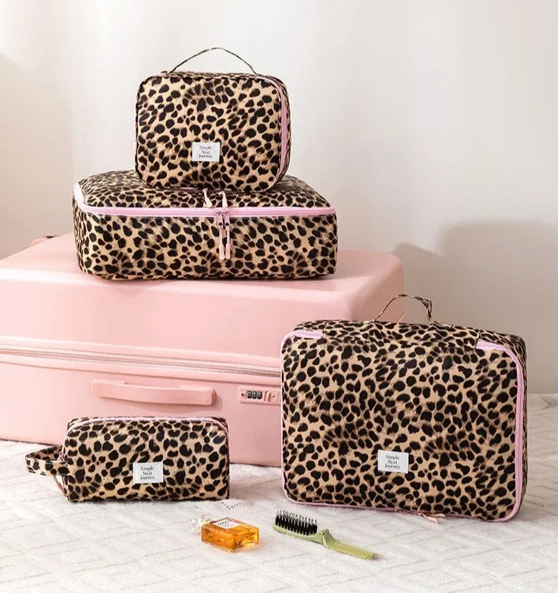 A set of leopard print travel makeup organizer bags in pink and black on a pink box.