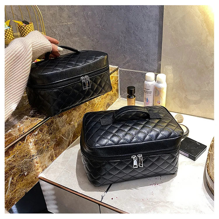 Black quilted makeup storage pouch with gold hardware resting on a marble surface.
