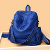 Un sac à dos en cuir souple bleu profond et rivetées, posé sur une surface en bois clair.