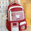 A maroon and white backpack featuring a checkered pattern and a cat design, worn by a person.