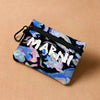 A dark blue floral print mini coin purse with a zipper and carabiner clip resting on a beige surface.