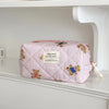 A pink and white quilted cosmetic makeup bag featuring small bear illustrations.