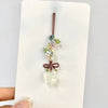 Un pendentif délicat avec un cluster de petites fleurs et feuilles sur un fil fin, suspendu d'une pierre claire et translucid