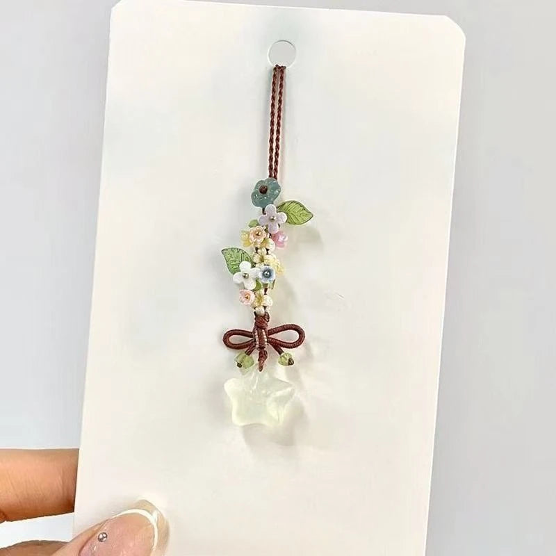 Un pendentif délicat avec un cluster de petites fleurs et feuilles sur un fil fin, suspendu d'une pierre claire et translucid