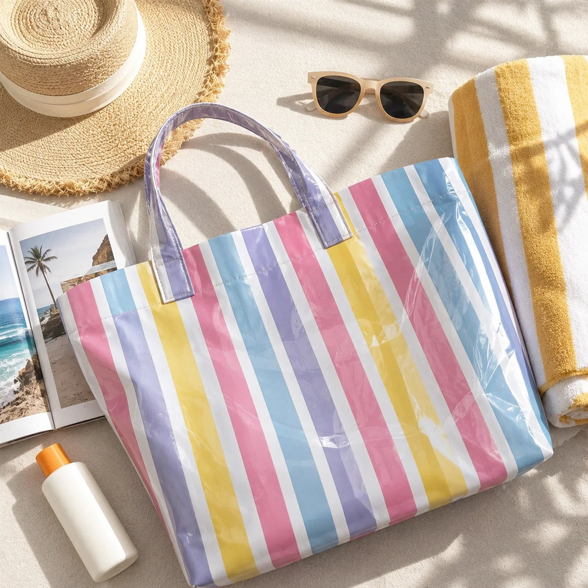 A striped PVC shoulder tote bag with purple handles lies next to a straw hat and sunglasses on a light surface.
