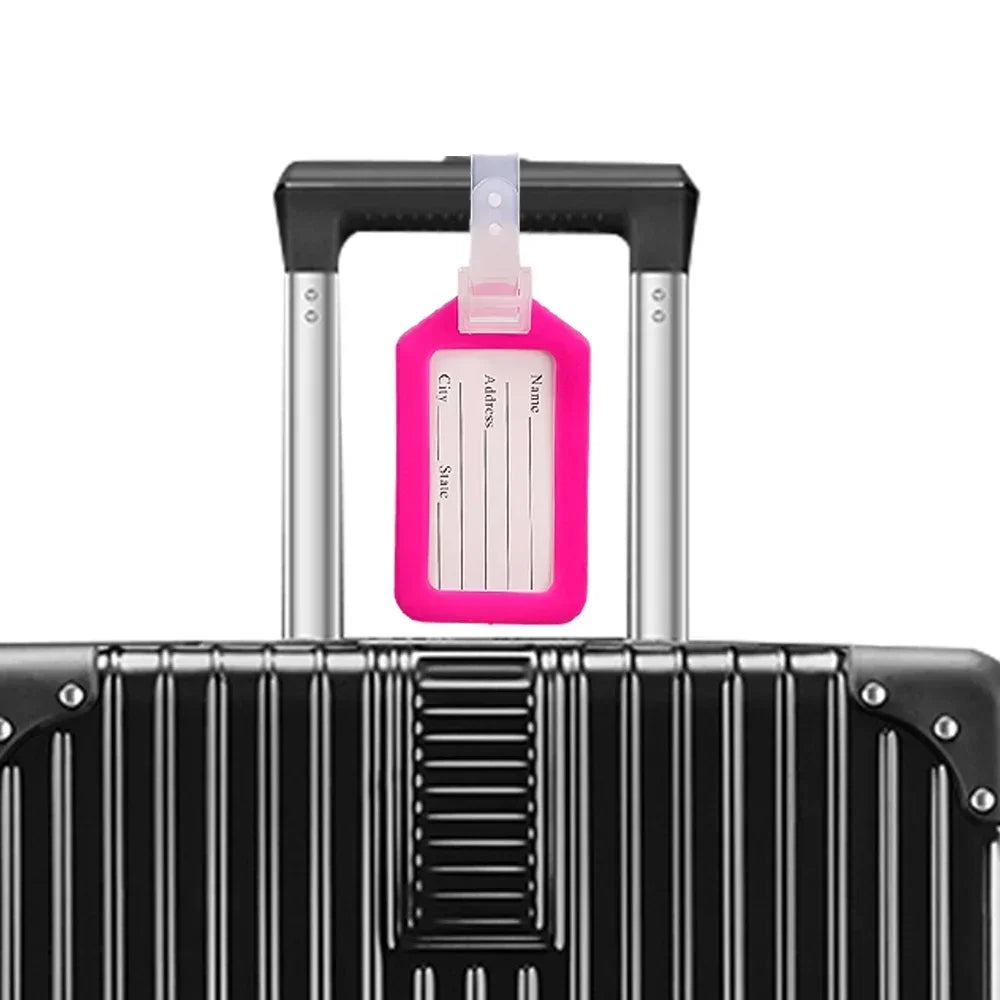 A black suitcase with a pink luggage tag attached to the handle.