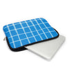 A bright blue plaid laptop sleeve with a black zipper is shown next to a white laptop.
