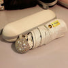 A compact white umbrella with gold accents and a rhinestone-covered handle is shown on a light surface.