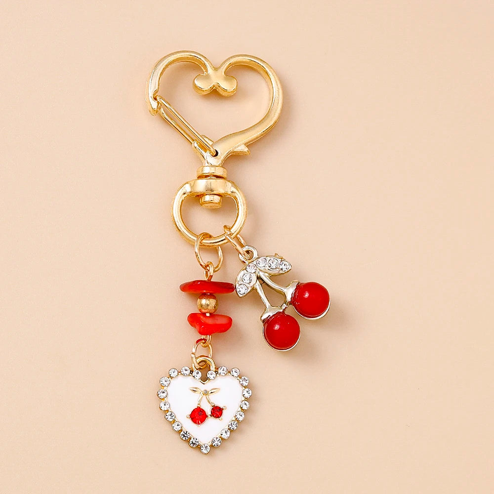 Gold-toned pearl bow heart keychain with red berries and white enamel detail