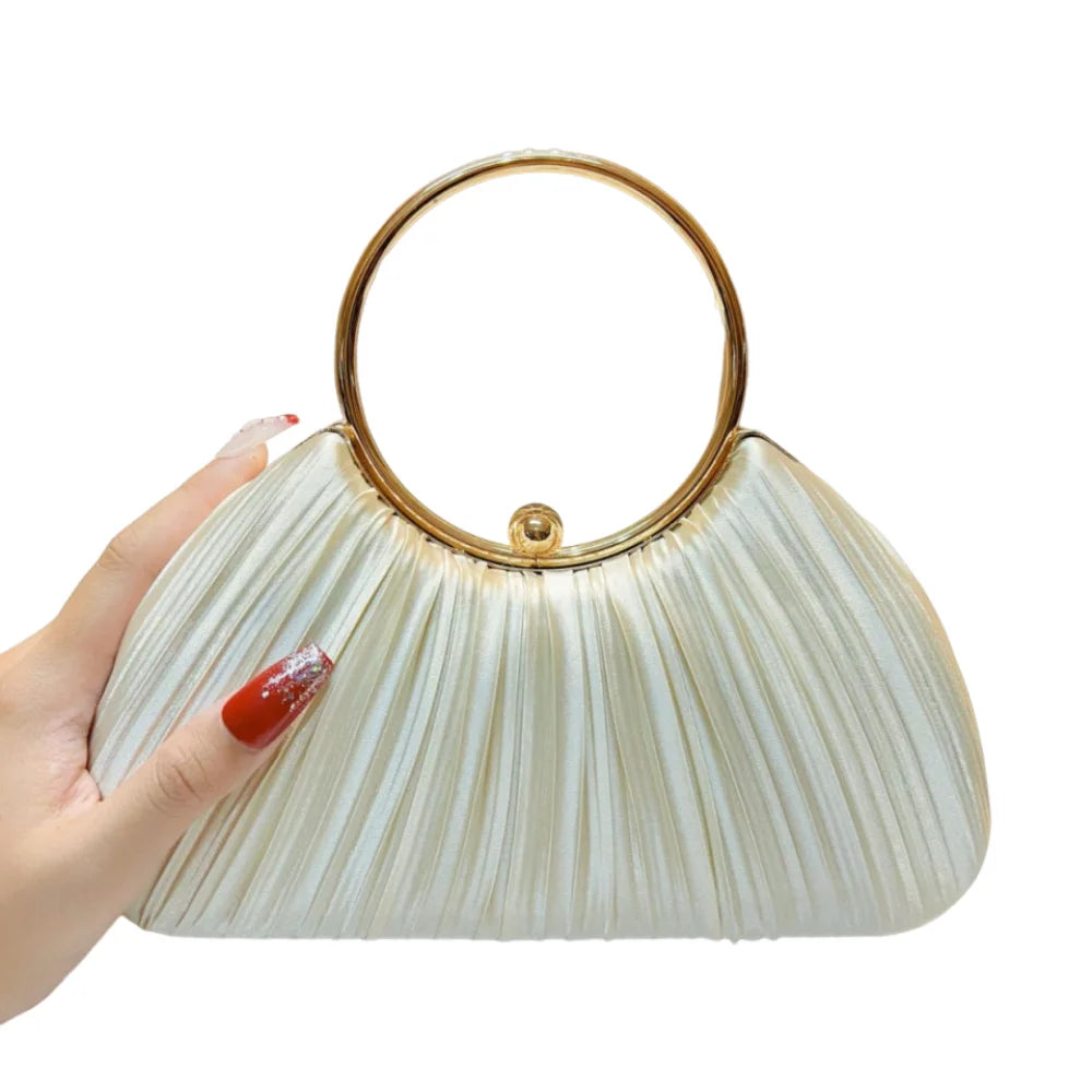 A hand holds an elegant satin pleated evening clutch bag with a gold rim and light beige fabric.