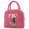 A pink insulated canvas lunch bag featuring a gold letter T and floral embroidery.