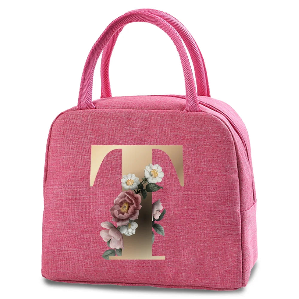 A pink insulated canvas lunch bag featuring a gold letter T and floral embroidery.