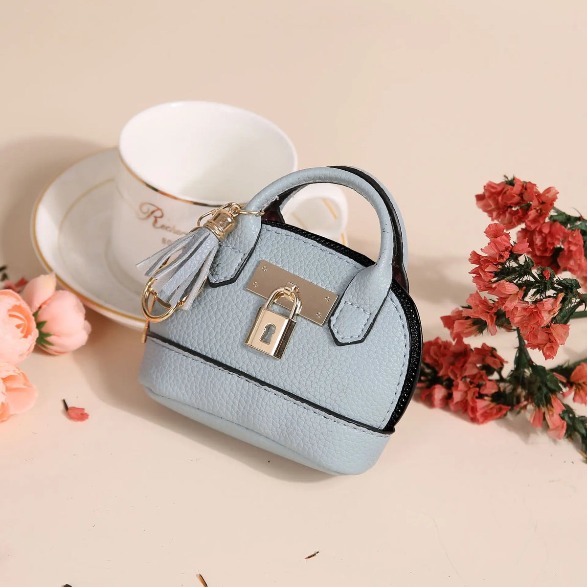 Portefeuille/porte-monnaie en plastique PVC bleu clair de luxe, porte-clés, posé sur une surface beige à côté d'une tasse bla