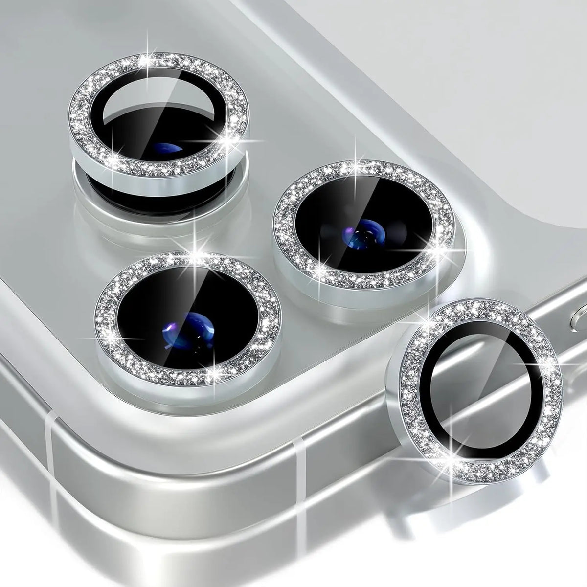 A close-up view of a glitter diamond camera lens protector with a metal frame for an iPhone, showing multiple lenses.