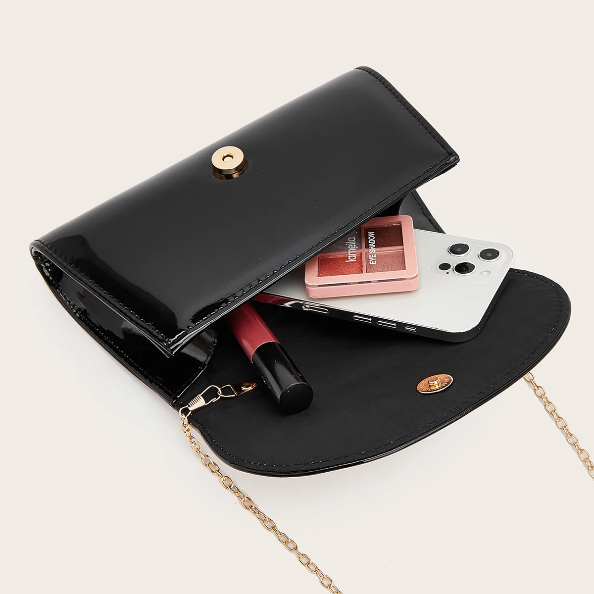 A black elegant clutch purse is shown open, containing a smartphone and a red lipstick.
