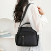 A woman is wearing a black multi-pocket shoulder crossbody bag over a white shirt.