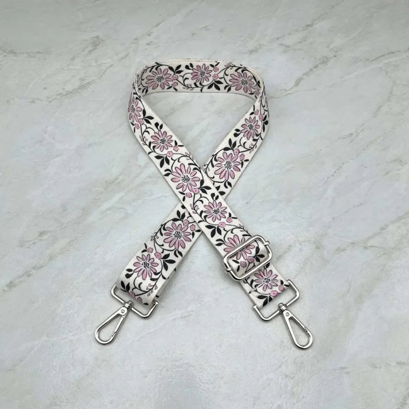 A beige and pink floral patterned adjustable crossbody strap for a handbag.