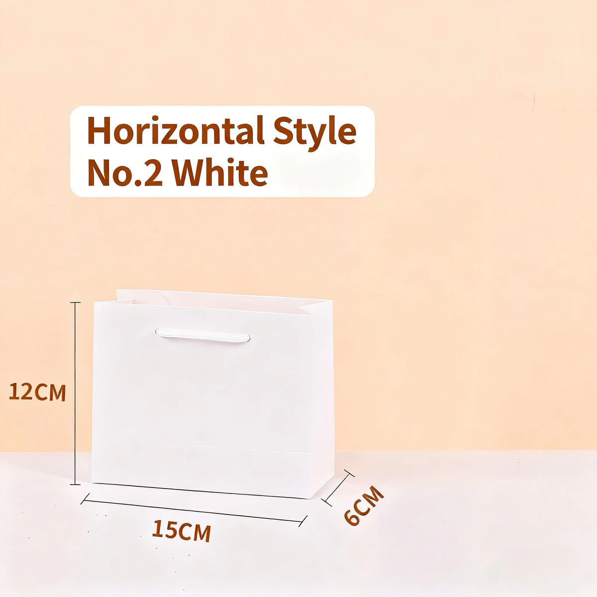 Una bolsa de regalo blanca y horizontal junto a una regla que mide sus dimensiones.